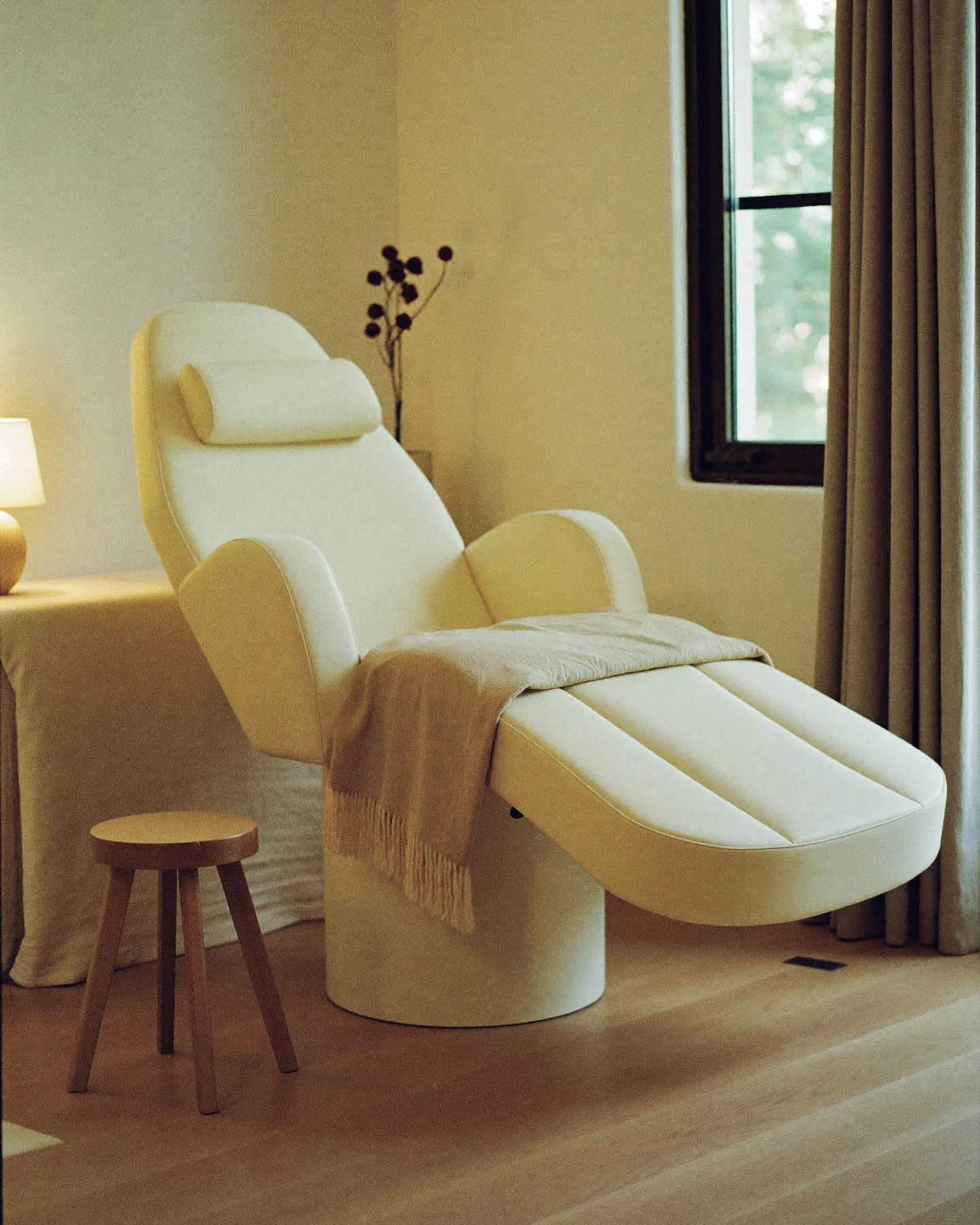 Una sala de tratamiento en Redefyn Aesthetics, el sillón reclinado con una manta de lana lista, y luz natural de la ventana