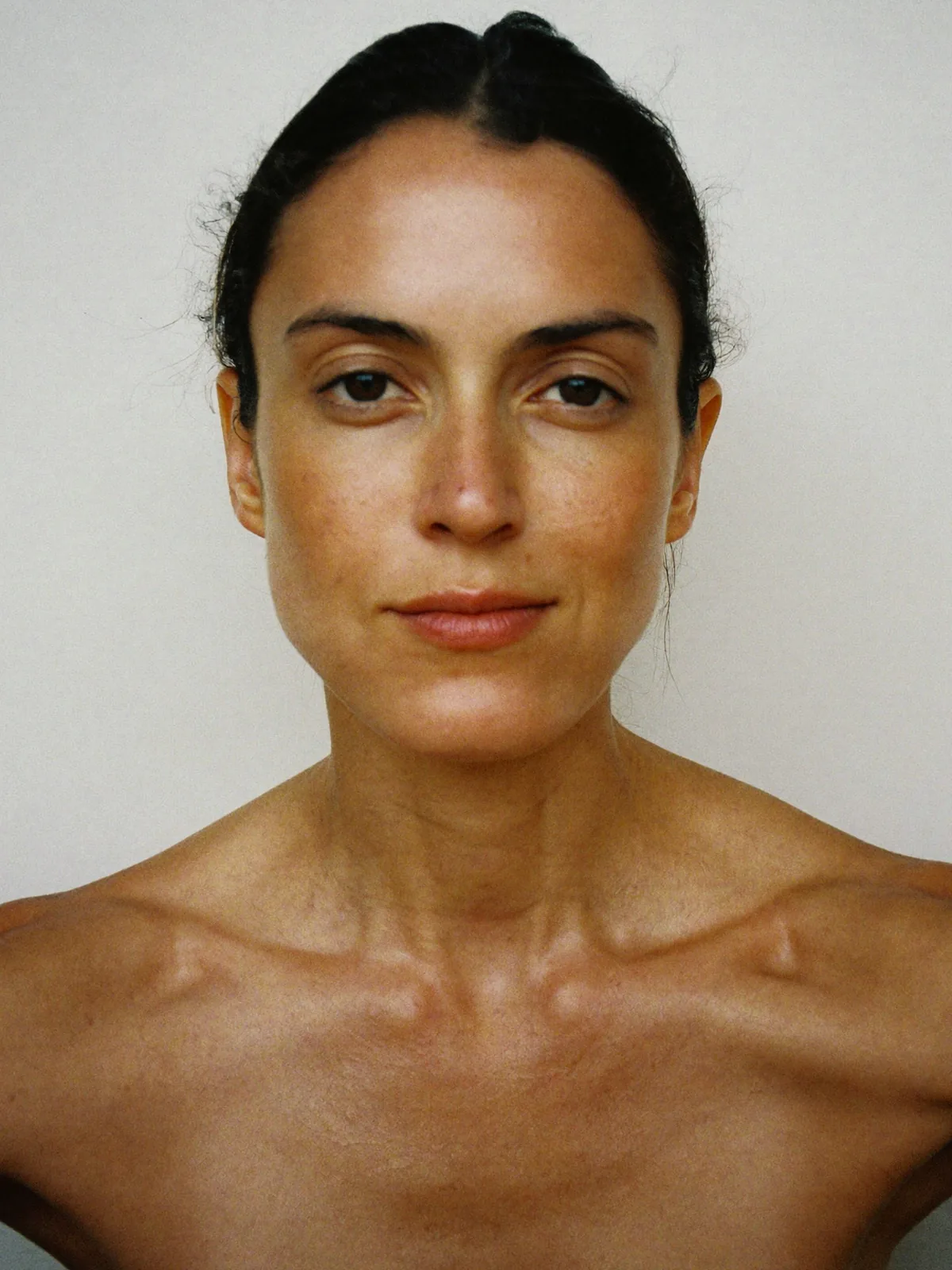 Una mujer con la piel recién lavada, sin maquillaje, y el cabello húmedo